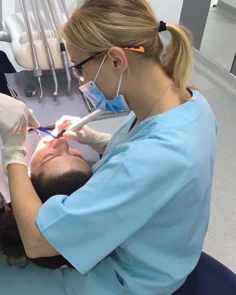 A dentist and assistant treating a patient at our partner clinic in Bucharest